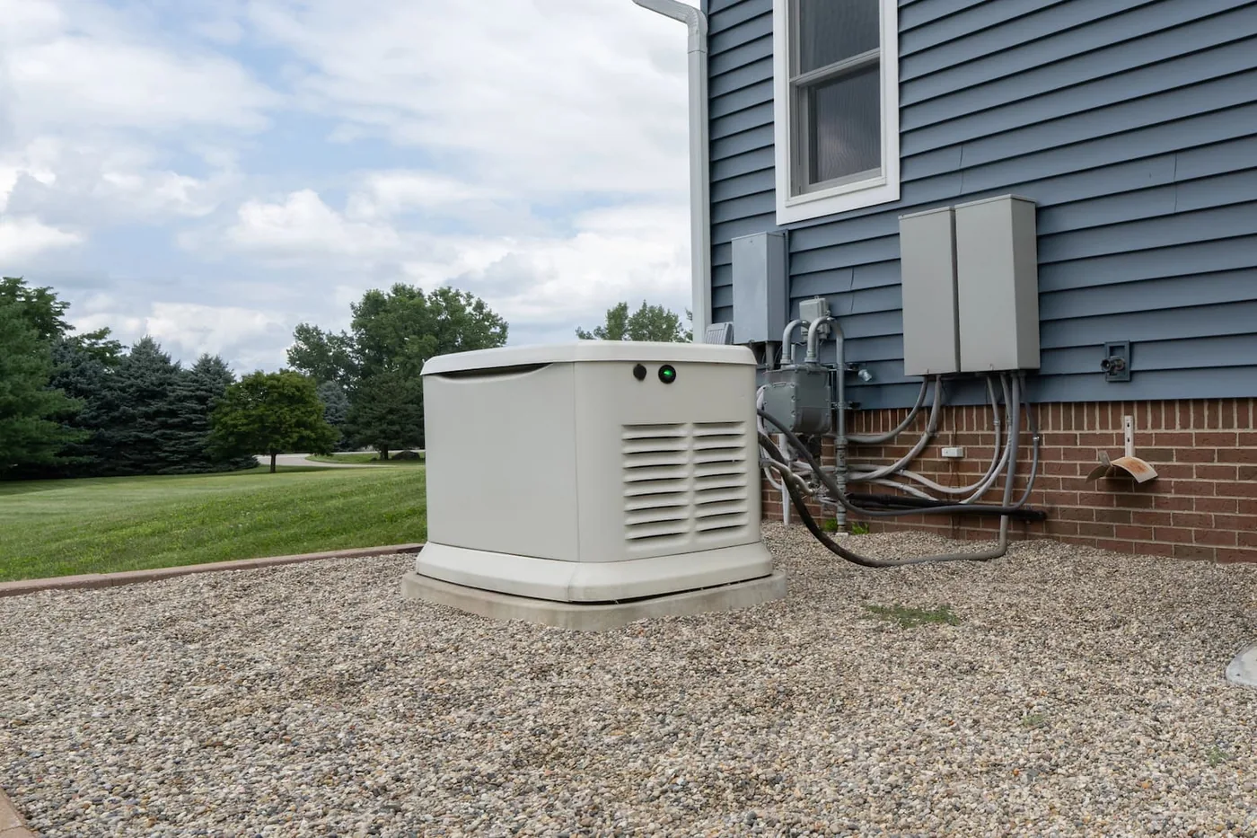 The wall tie-in on a standby install: the gas line and regulator, the automatic transfer switch, and a service disconnect mounted beside the generator.